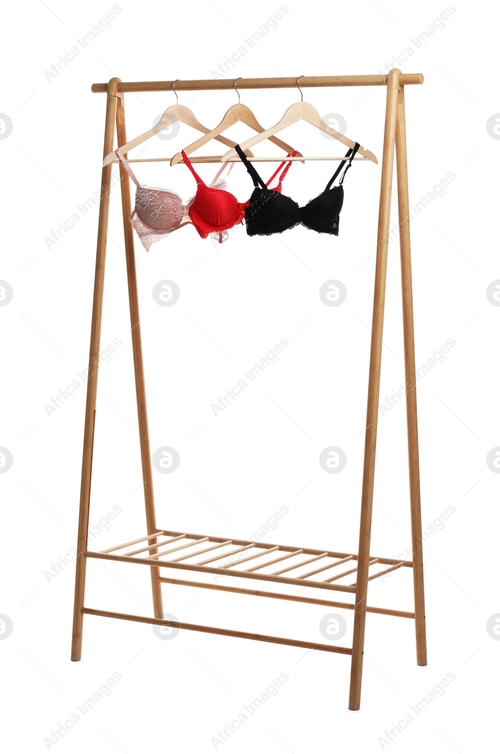 Photo of Hangers with beautiful bras on wooden rack against white background