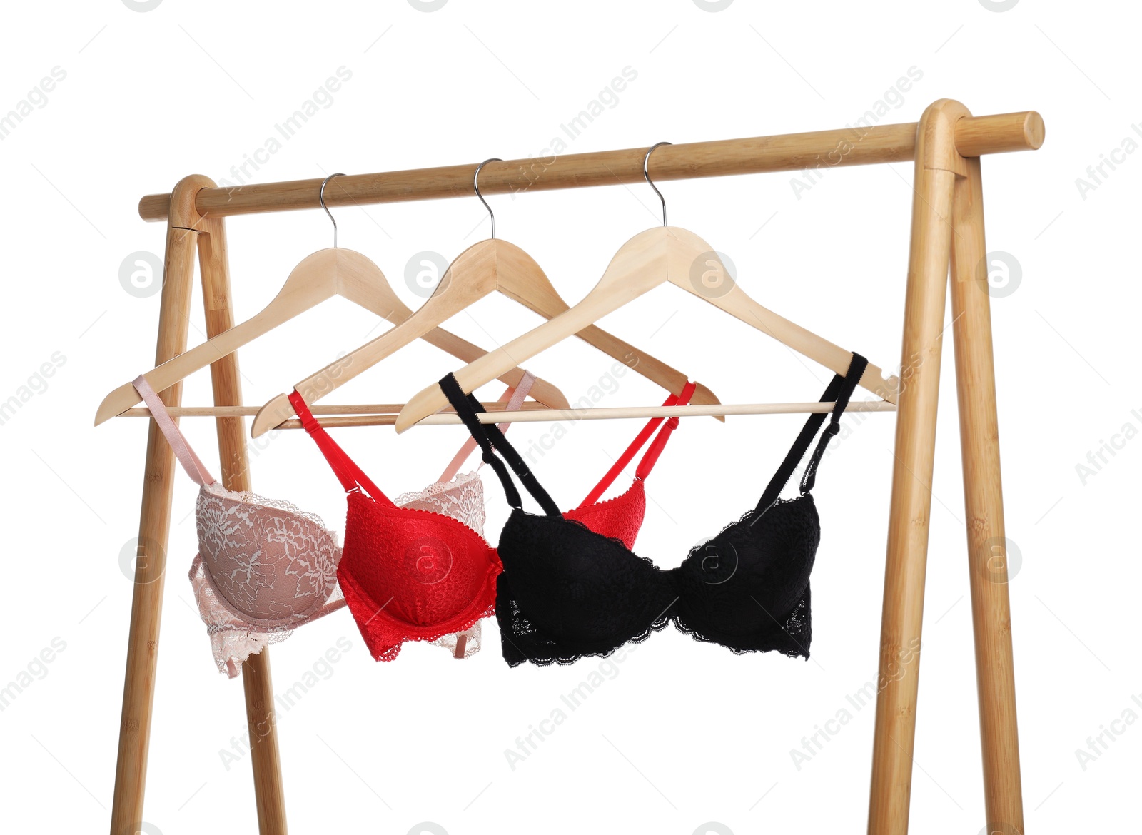 Photo of Hangers with beautiful bras on wooden rack against white background