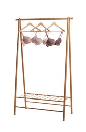 Photo of Hangers with beautiful bras on wooden rack against white background