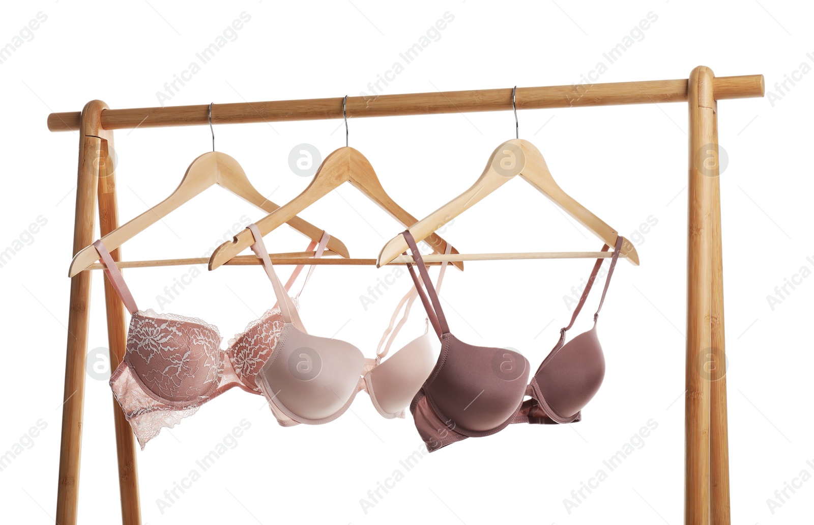 Photo of Hangers with beautiful bras on wooden rack against white background