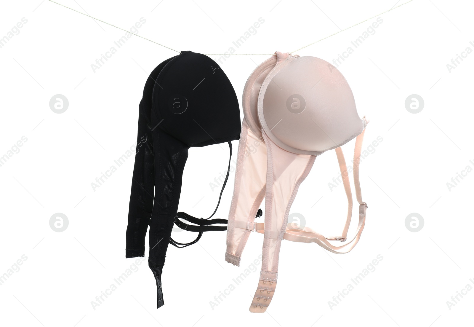 Photo of Beautiful bras hanging on rope against white background