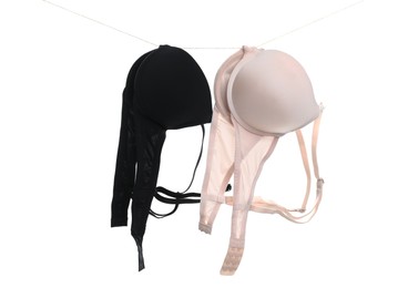 Photo of Beautiful bras hanging on rope against white background