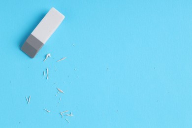 Photo of One eraser and scraps on light blue background, top view. Space for text