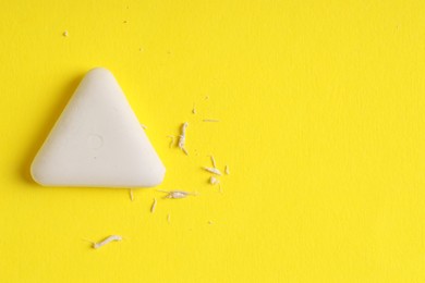 Photo of One eraser and scraps on yellow background, top view. Space for text