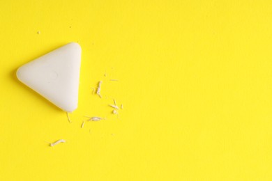 Photo of One eraser and scraps on yellow background, top view. Space for text