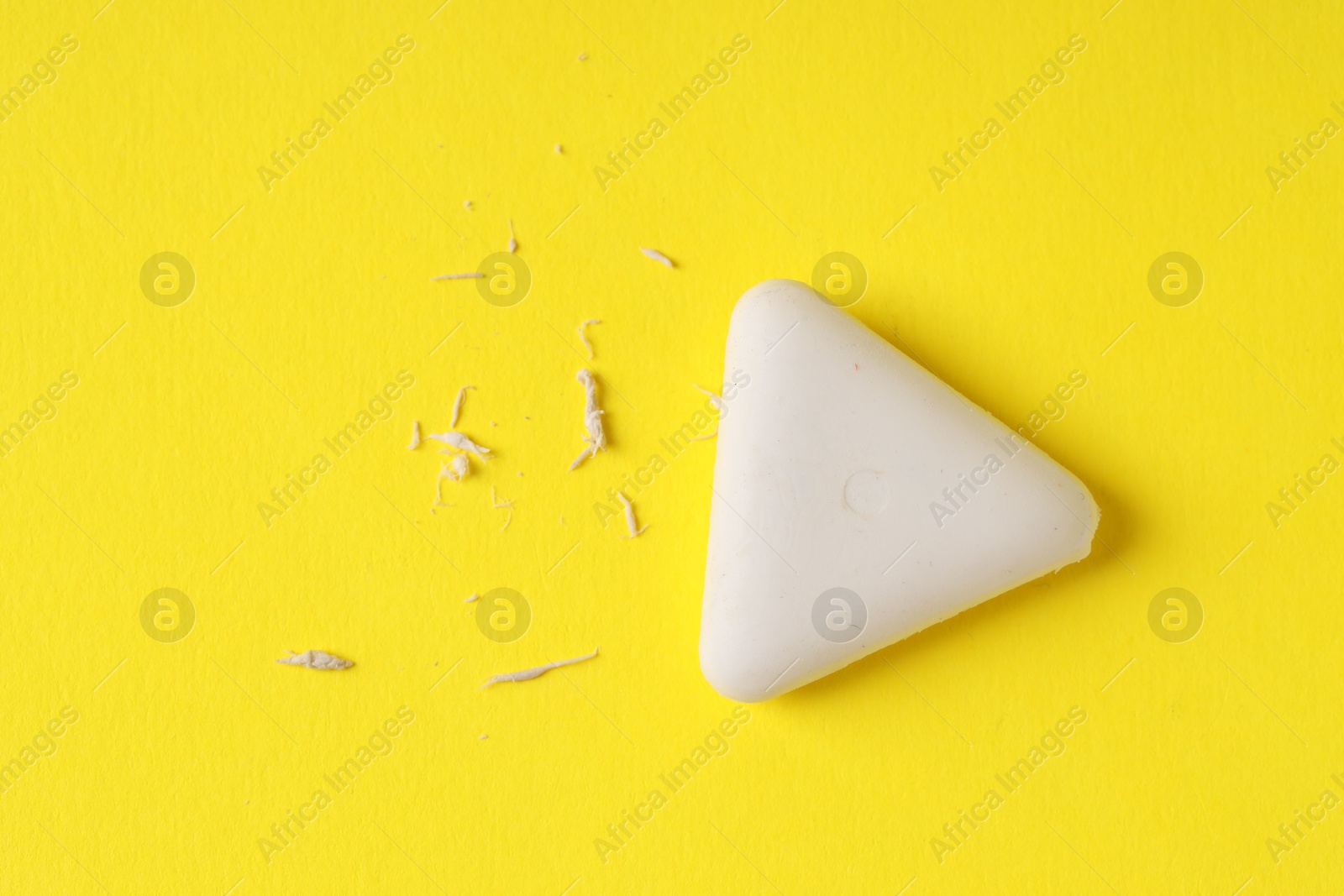 Photo of One eraser and scraps on yellow background, top view