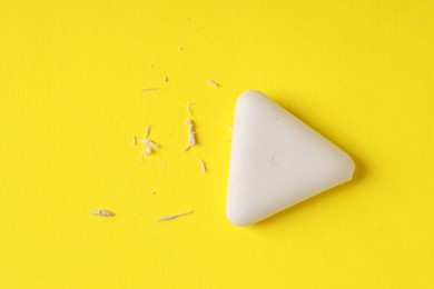 Photo of One eraser and scraps on yellow background, top view