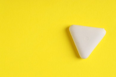 Photo of One eraser on yellow background, top view. Space for text