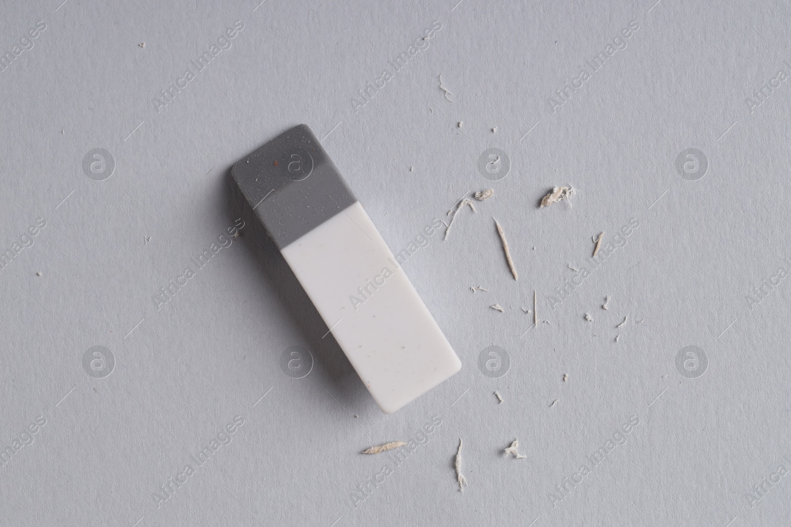 Photo of One eraser and scraps on grey background, top view