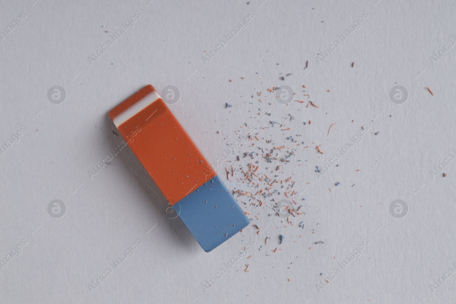 Photo of One eraser and scraps on grey background, top view