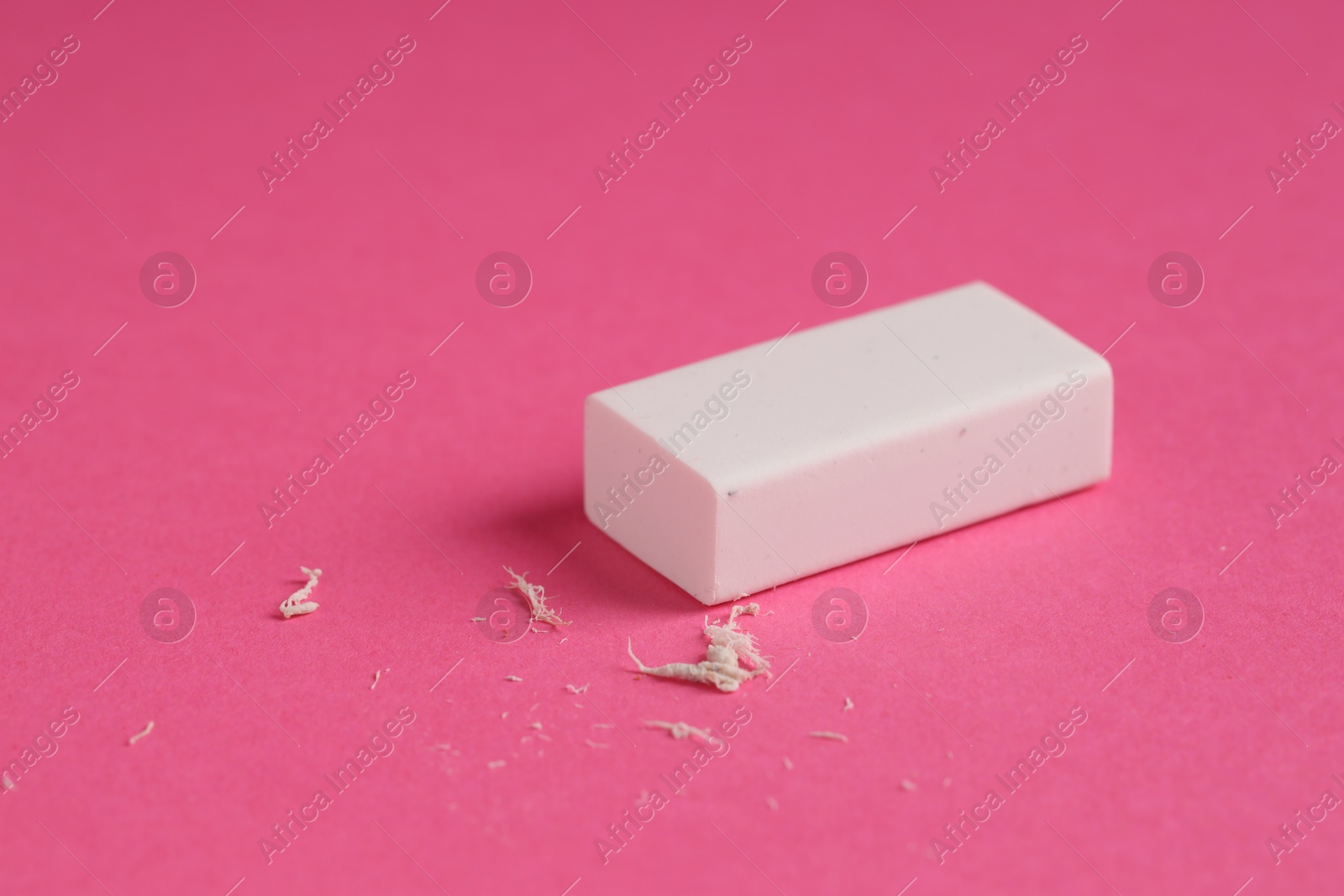 Photo of One eraser and scraps on pink background, closeup