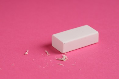 Photo of One eraser and scraps on pink background, closeup