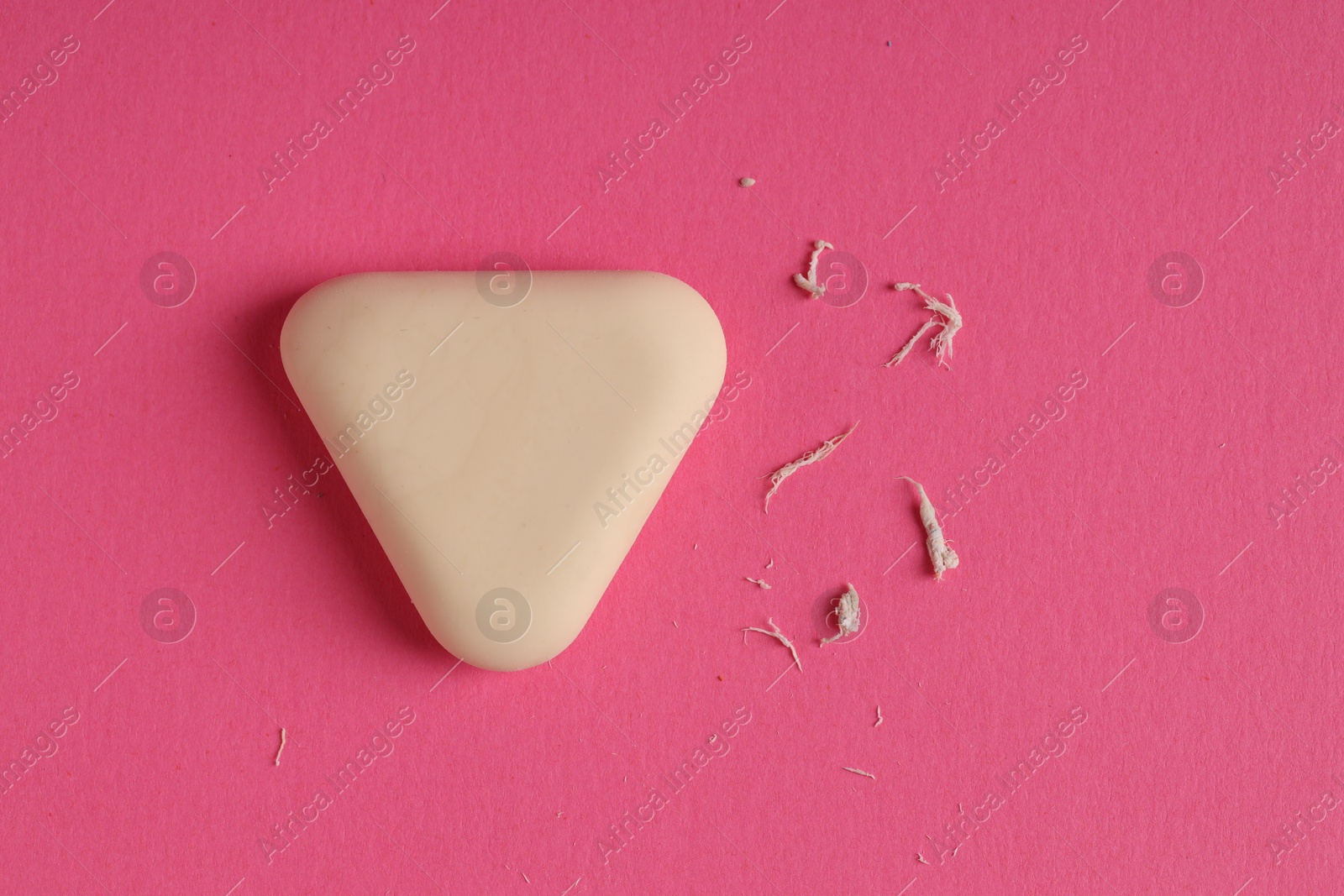 Photo of One eraser and scraps on pink background, top view