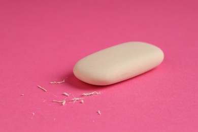 Photo of One eraser and scraps on pink background, closeup