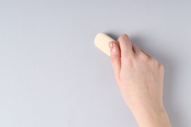 Photo of Woman using eraser on grey background, closeup. Space for text