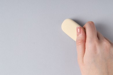 Photo of Woman using eraser on grey background, closeup. Space for text