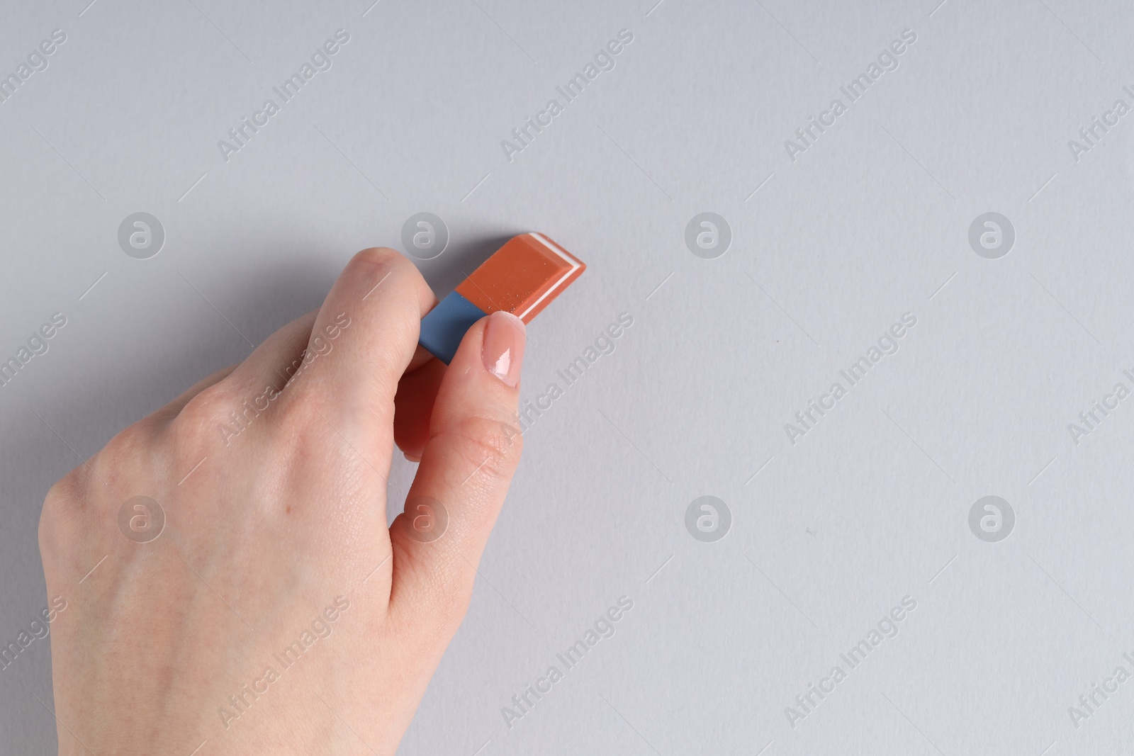 Photo of Woman using eraser on grey background, closeup. Space for text