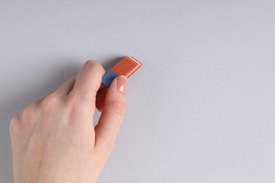 Photo of Woman using eraser on grey background, closeup. Space for text