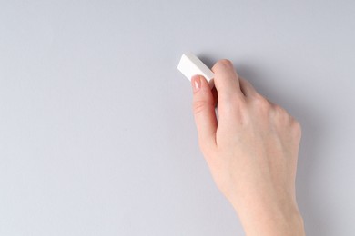 Photo of Woman using eraser on grey background, closeup