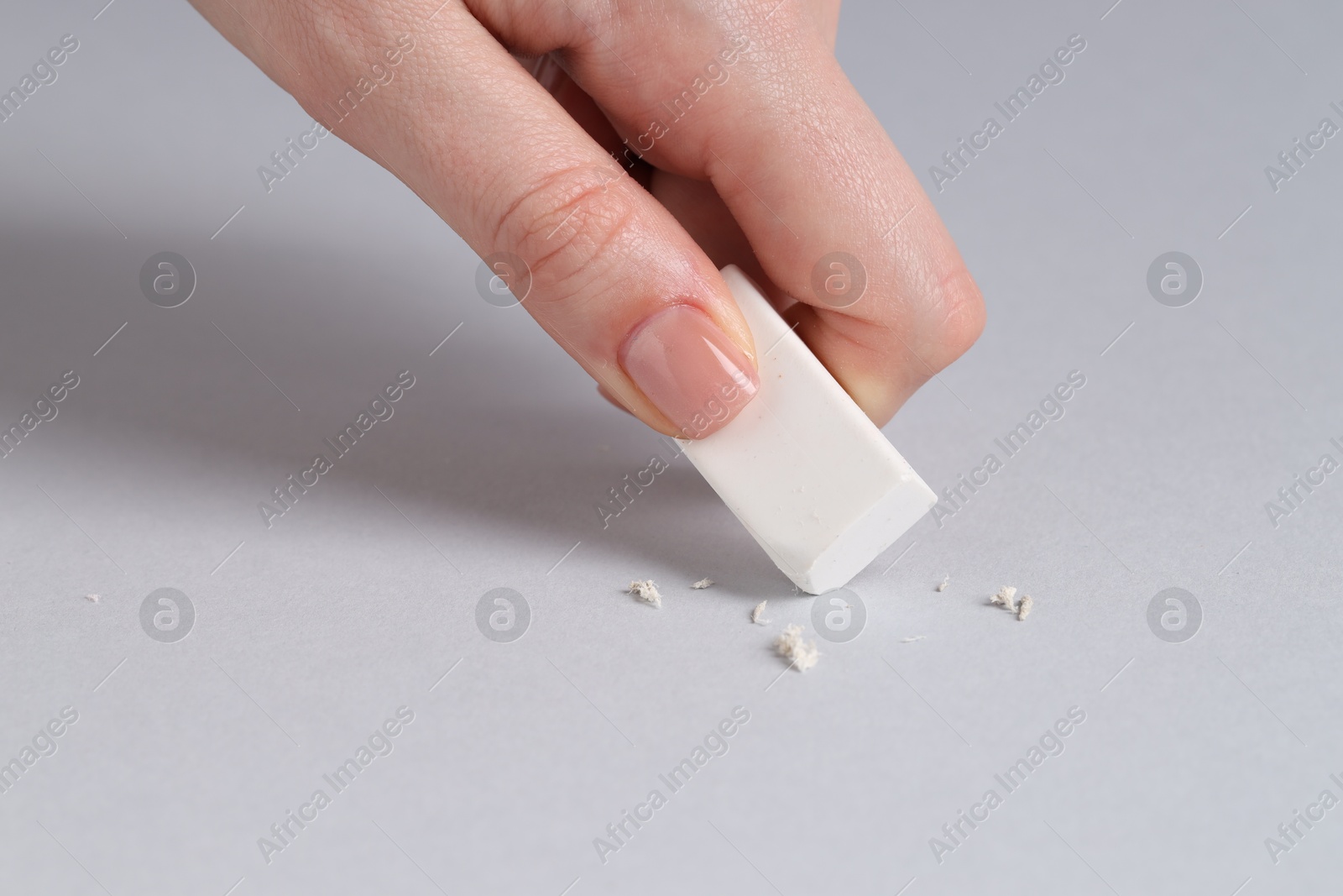 Photo of Woman using eraser on grey background, closeup