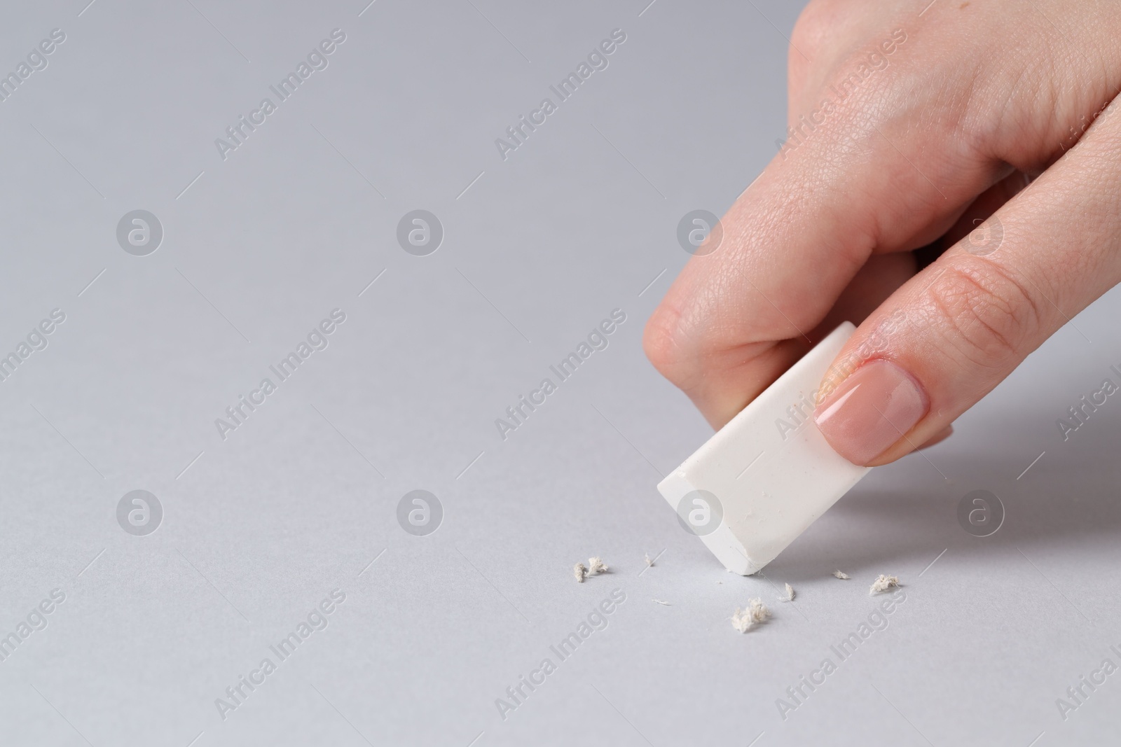 Photo of Woman using eraser on grey background, closeup. Space for text