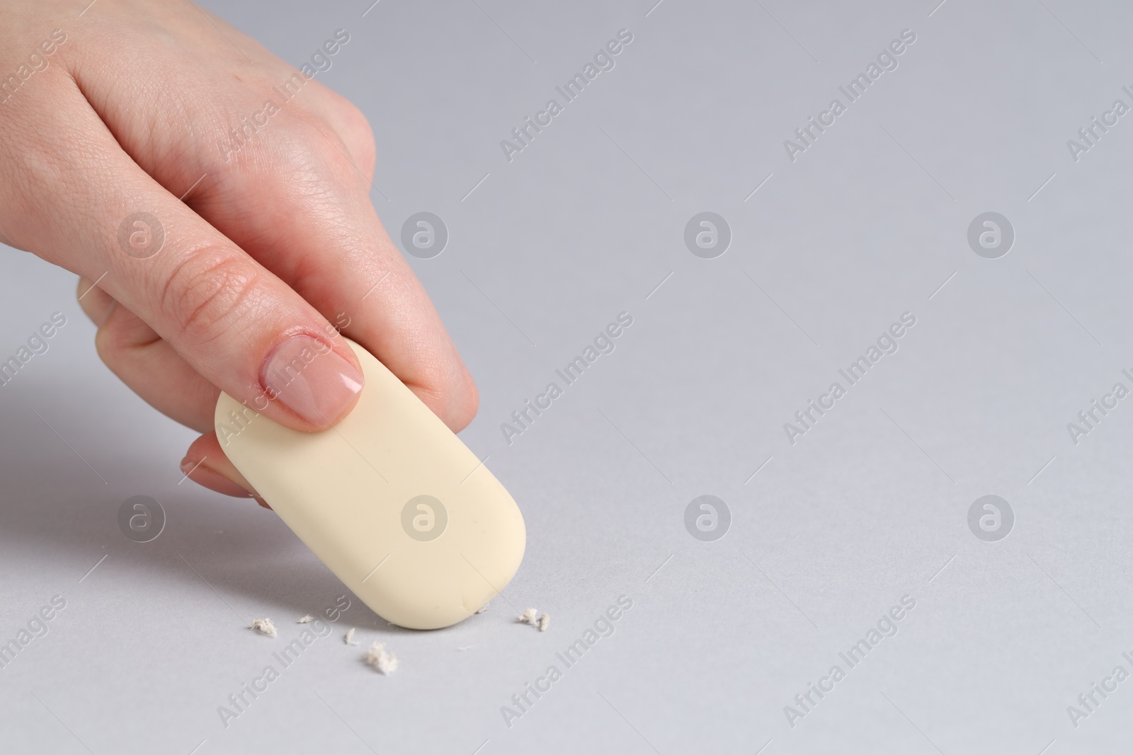 Photo of Woman using eraser on grey background, closeup. Space for text