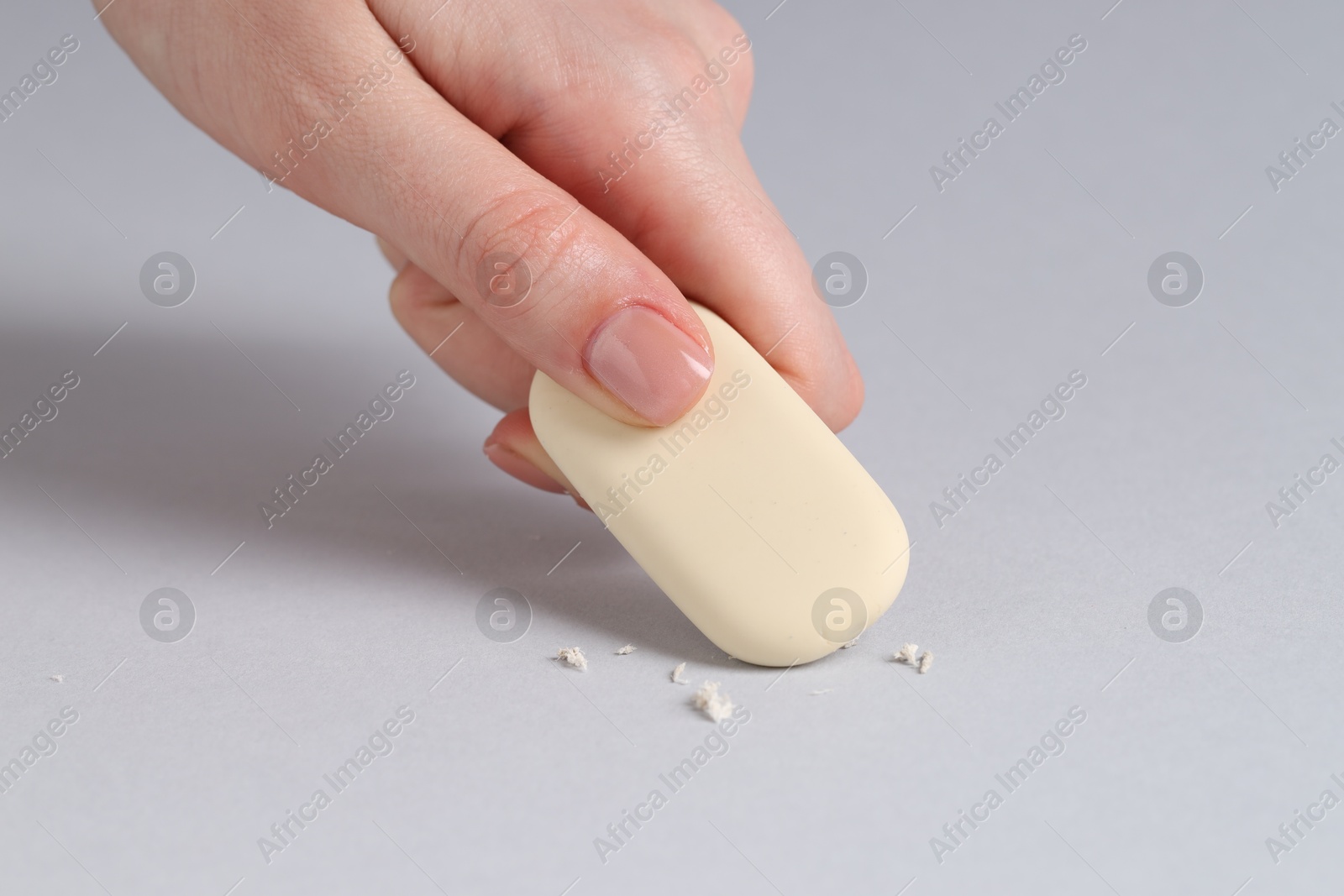 Photo of Woman using eraser on grey background, closeup