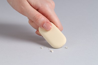 Photo of Woman using eraser on grey background, closeup