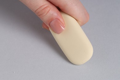 Woman using eraser on grey background, closeup