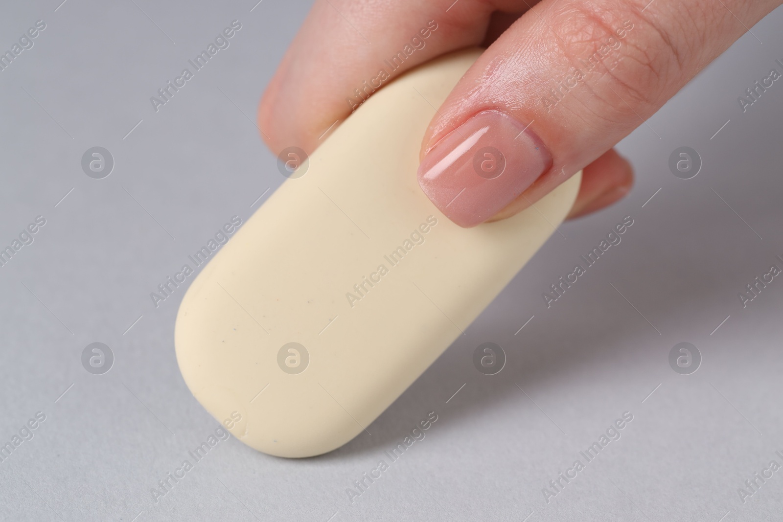 Photo of Woman using eraser on grey background, closeup