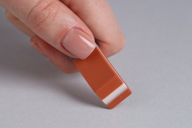 Photo of Woman using eraser on grey background, closeup