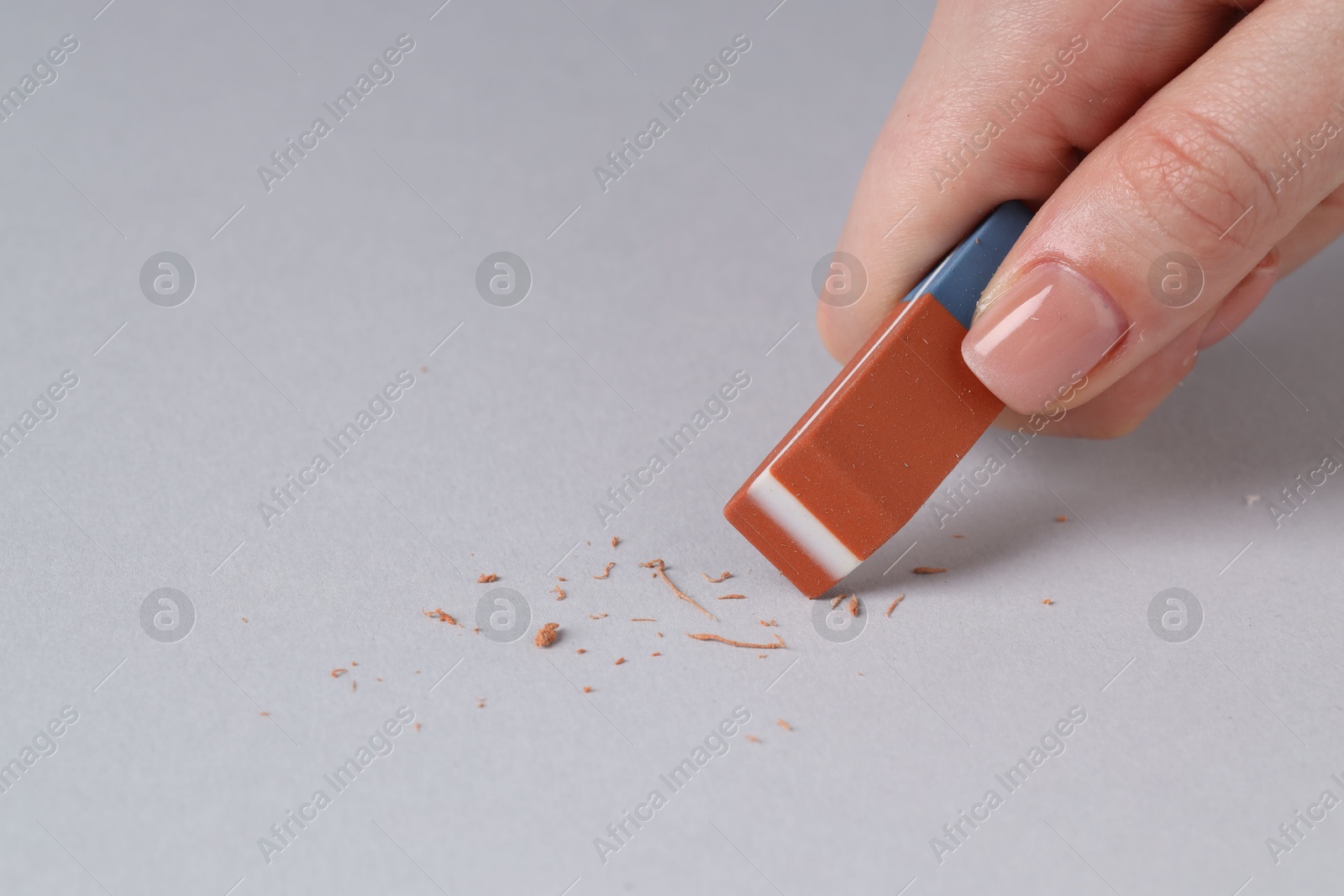 Photo of Woman using eraser on grey background, closeup. Space for text