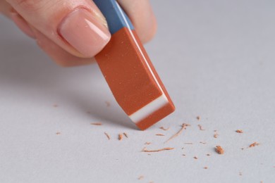 Photo of Woman using eraser on grey background, closeup