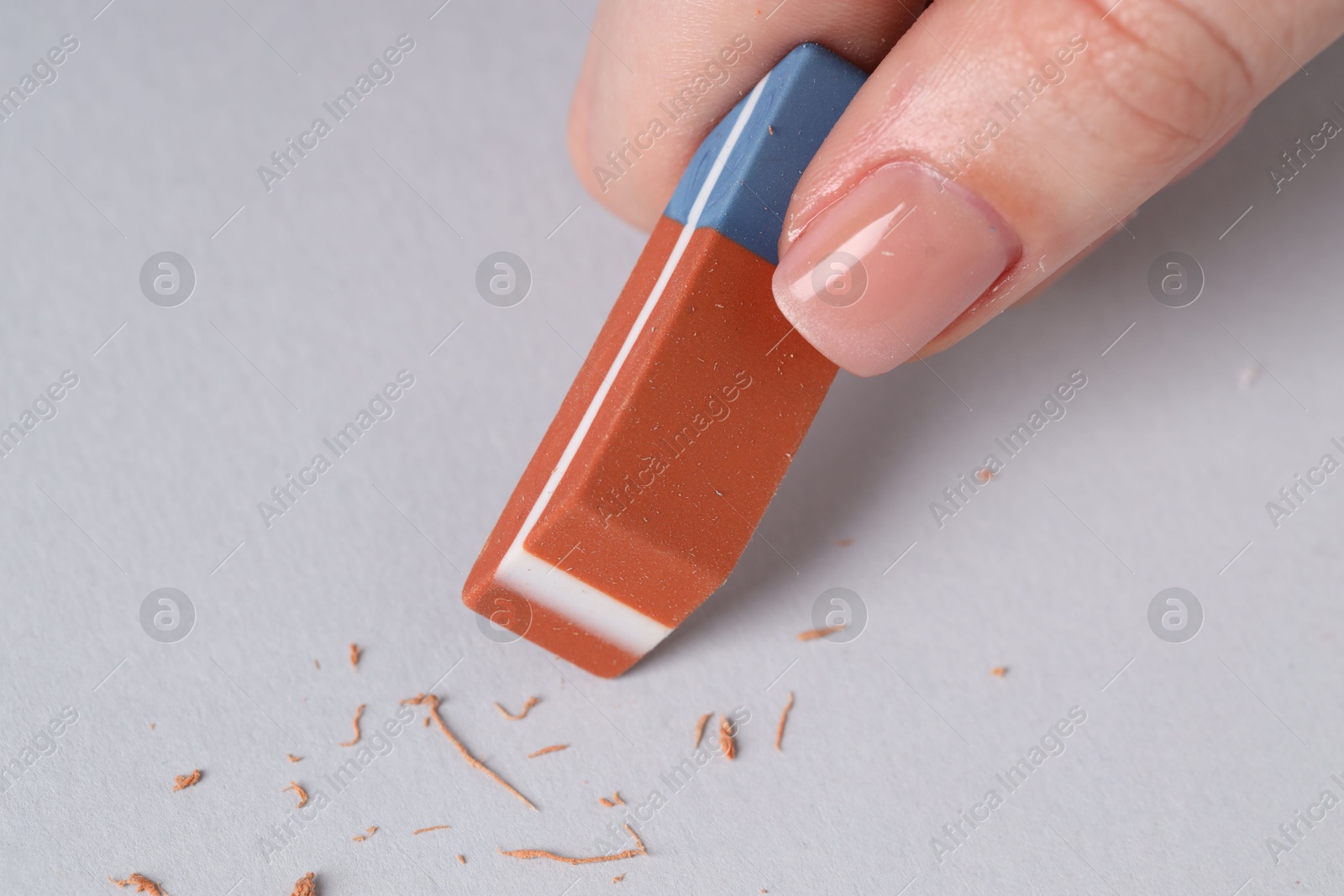 Photo of Woman using eraser on grey background, closeup