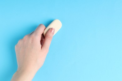 Photo of Woman using eraser on light blue background, closeup. Space for text