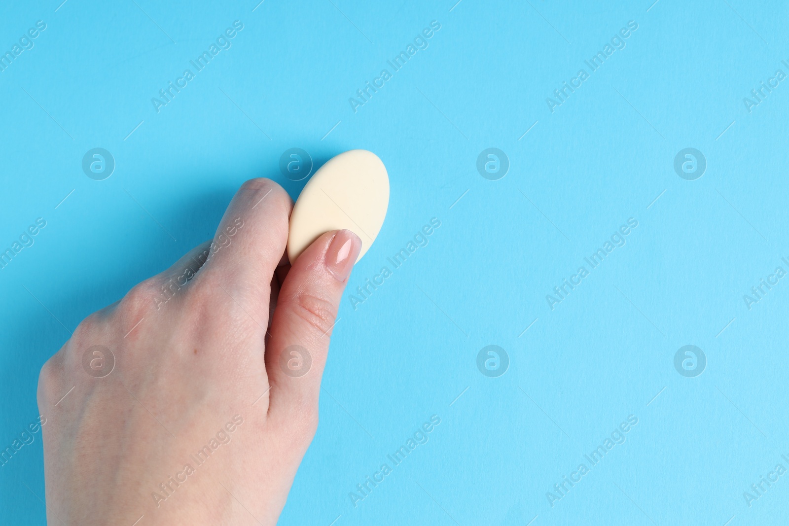 Photo of Woman using eraser on light blue background, closeup. Space for text