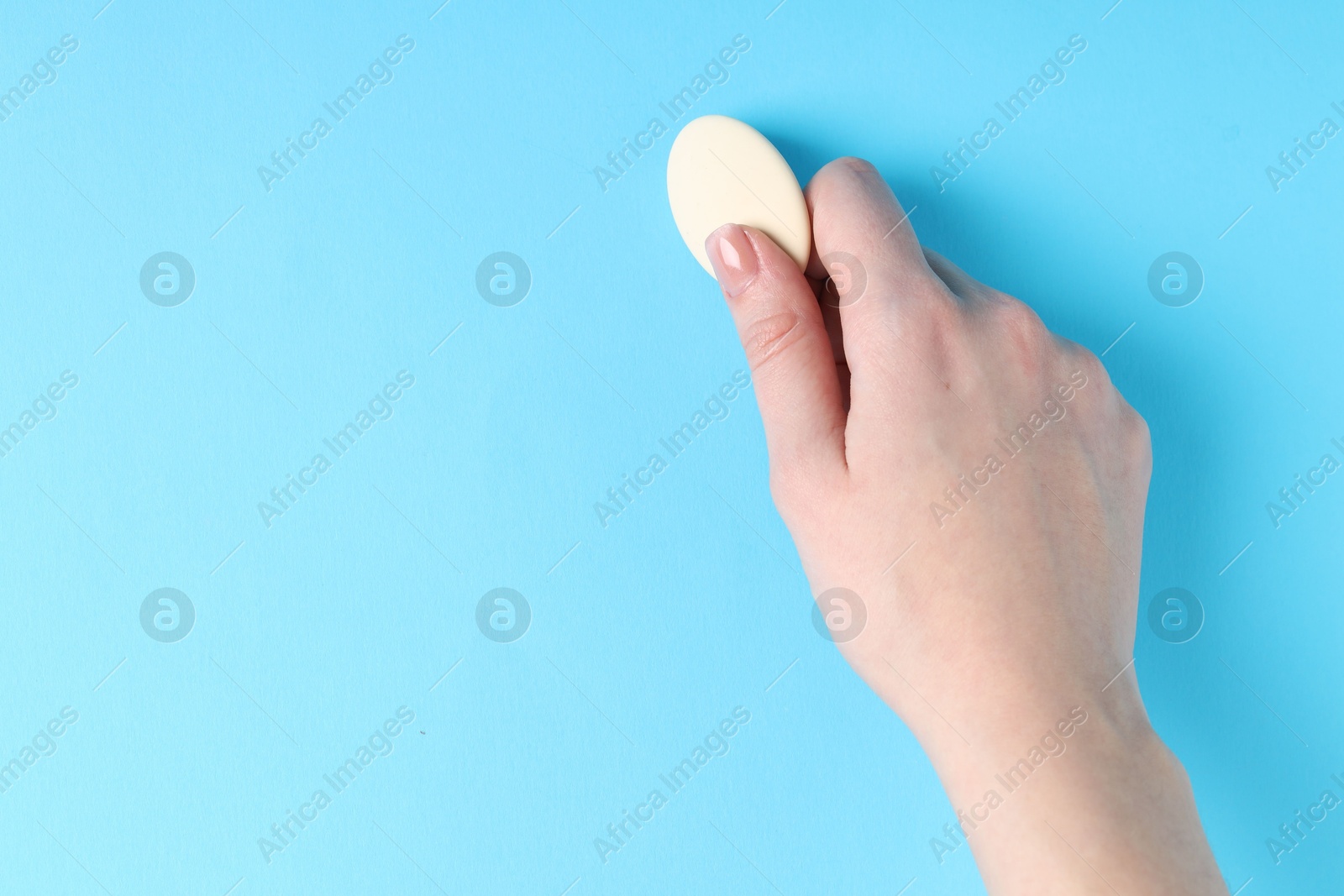 Photo of Woman using eraser on light blue background, closeup. Space for text