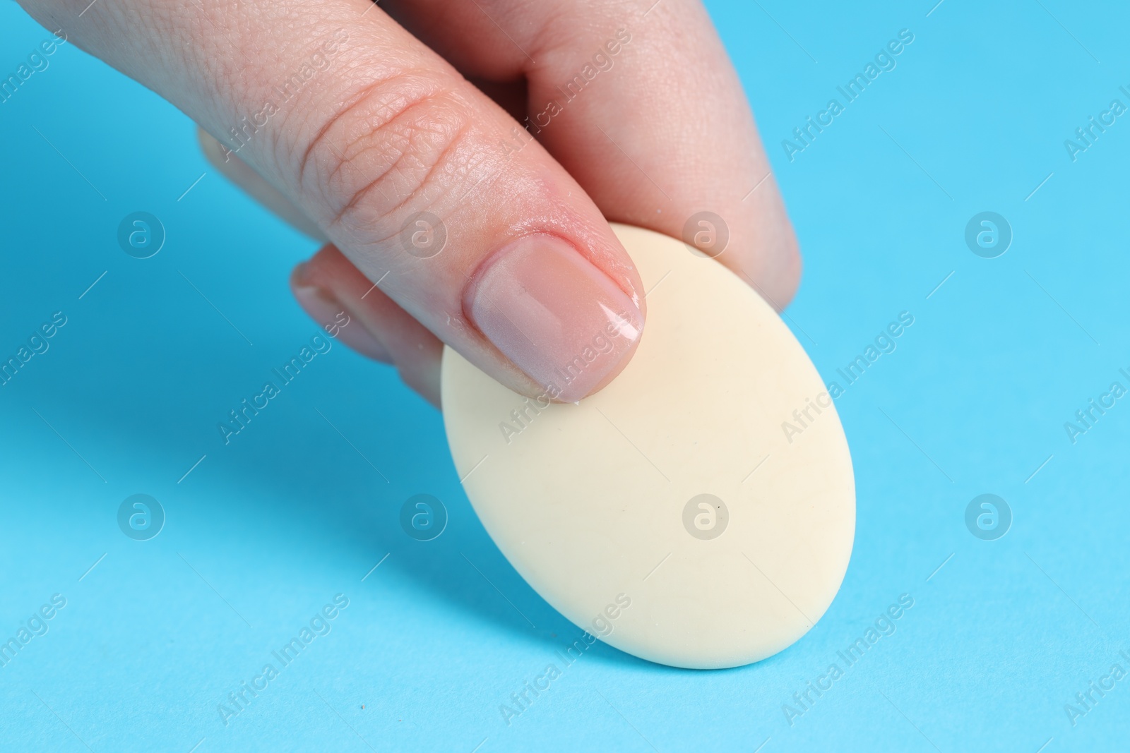 Photo of Woman using eraser on light blue background, closeup