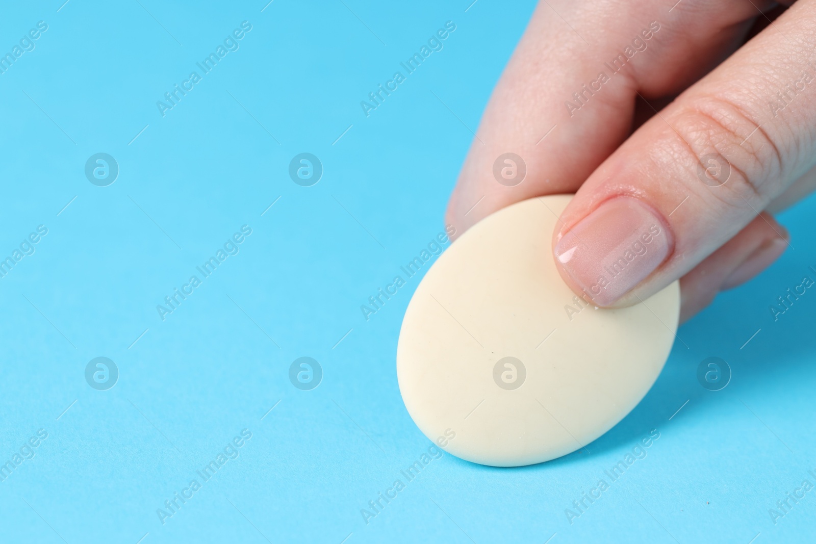 Photo of Woman using eraser on light blue background, closeup. Space for text