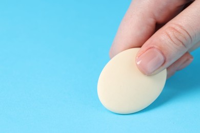 Photo of Woman using eraser on light blue background, closeup. Space for text