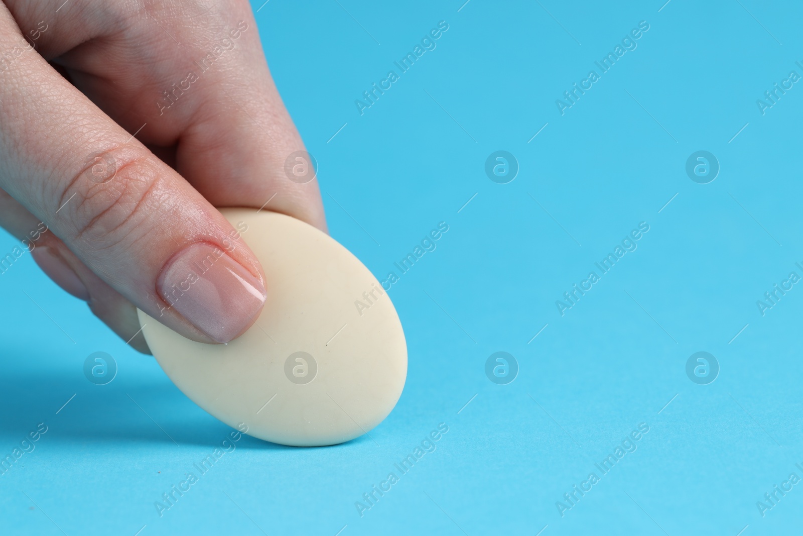 Photo of Woman using eraser on light blue background, closeup. Space for text