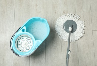 String mop and bucket with detergent on wooden floor, top view