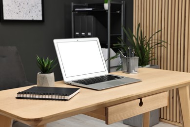 Photo of Comfortable workplace with modern laptop on wooden table indoors