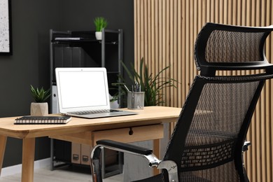 Photo of Comfortable workplace with modern laptop on wooden table indoors