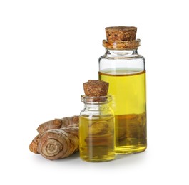 Photo of Bottles of turmeric essential oil and raw roots isolated on white