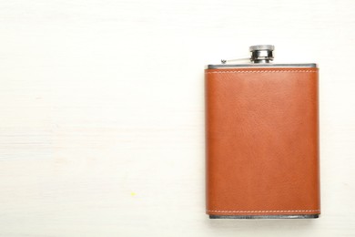 Photo of One hip flask on light wooden table, top view. Space for text