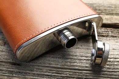 One hip flask on wooden table, closeup