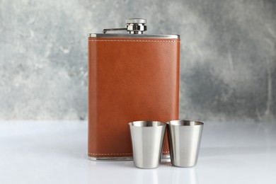 Photo of Hip flask and cups on white table