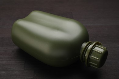 Photo of Green plastic canteen on wooden table, closeup