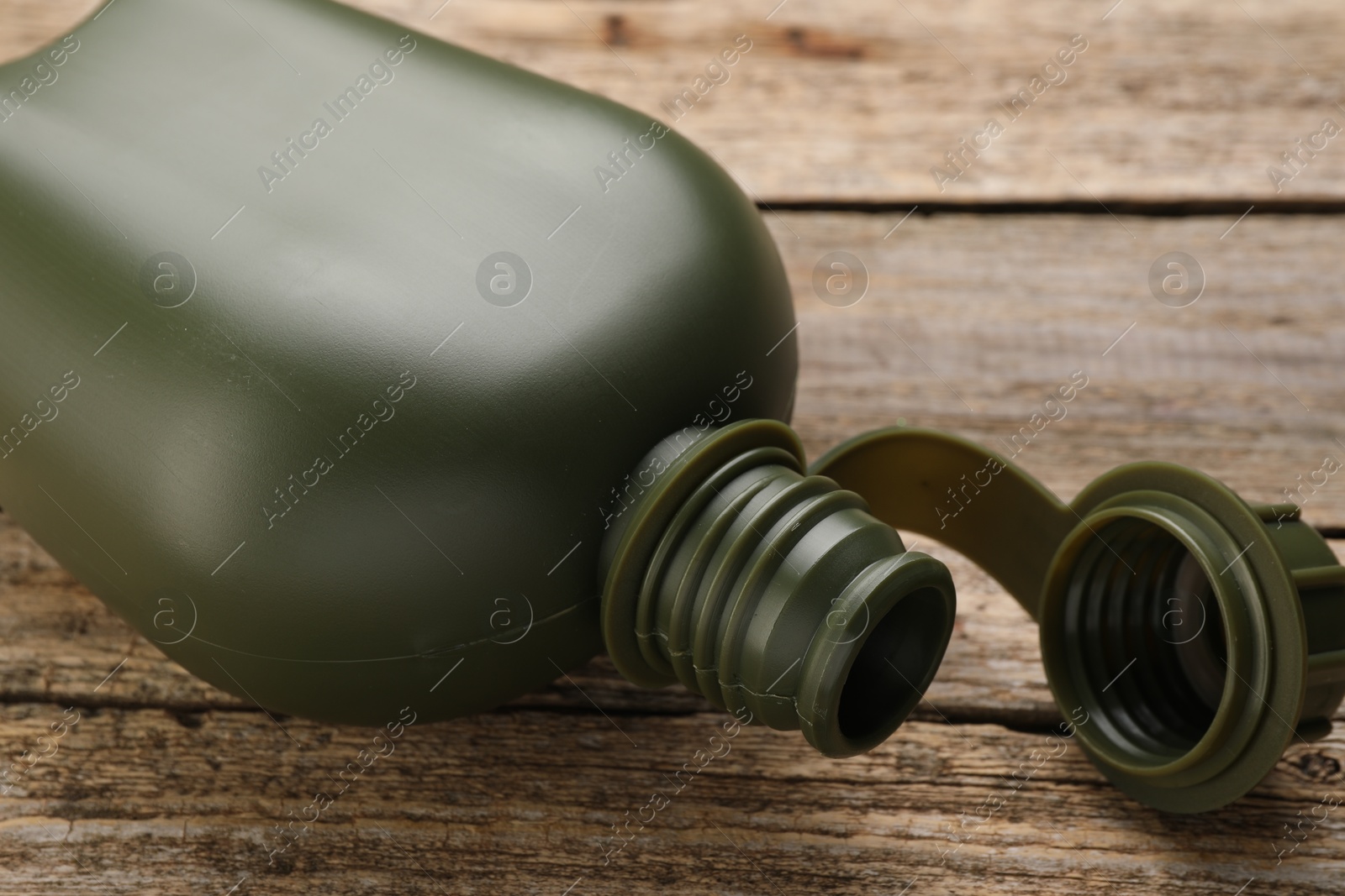 Photo of Green plastic canteen on wooden table, closeup